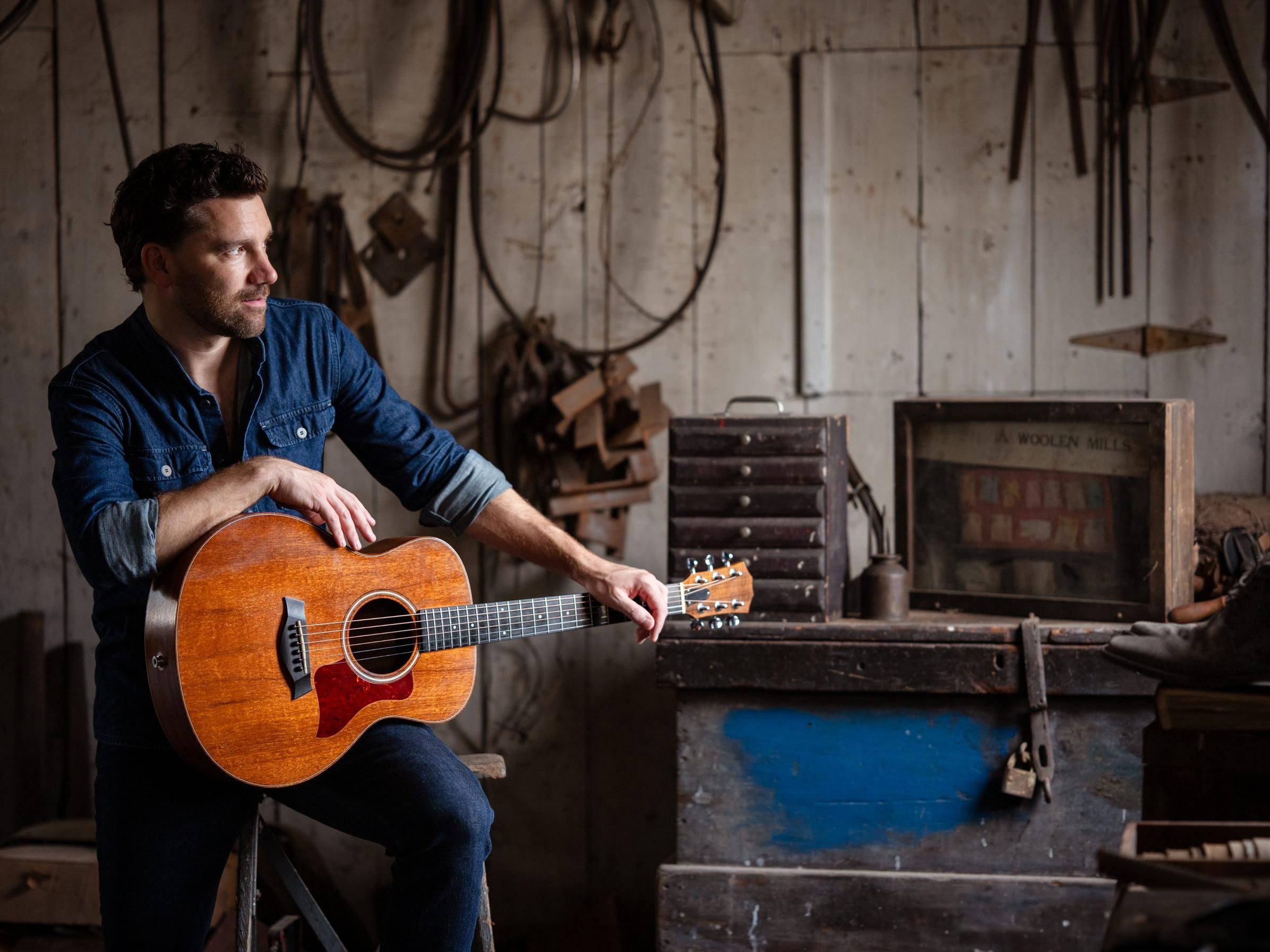 Picture of Evi Lev holding a guitar in a dusty shed