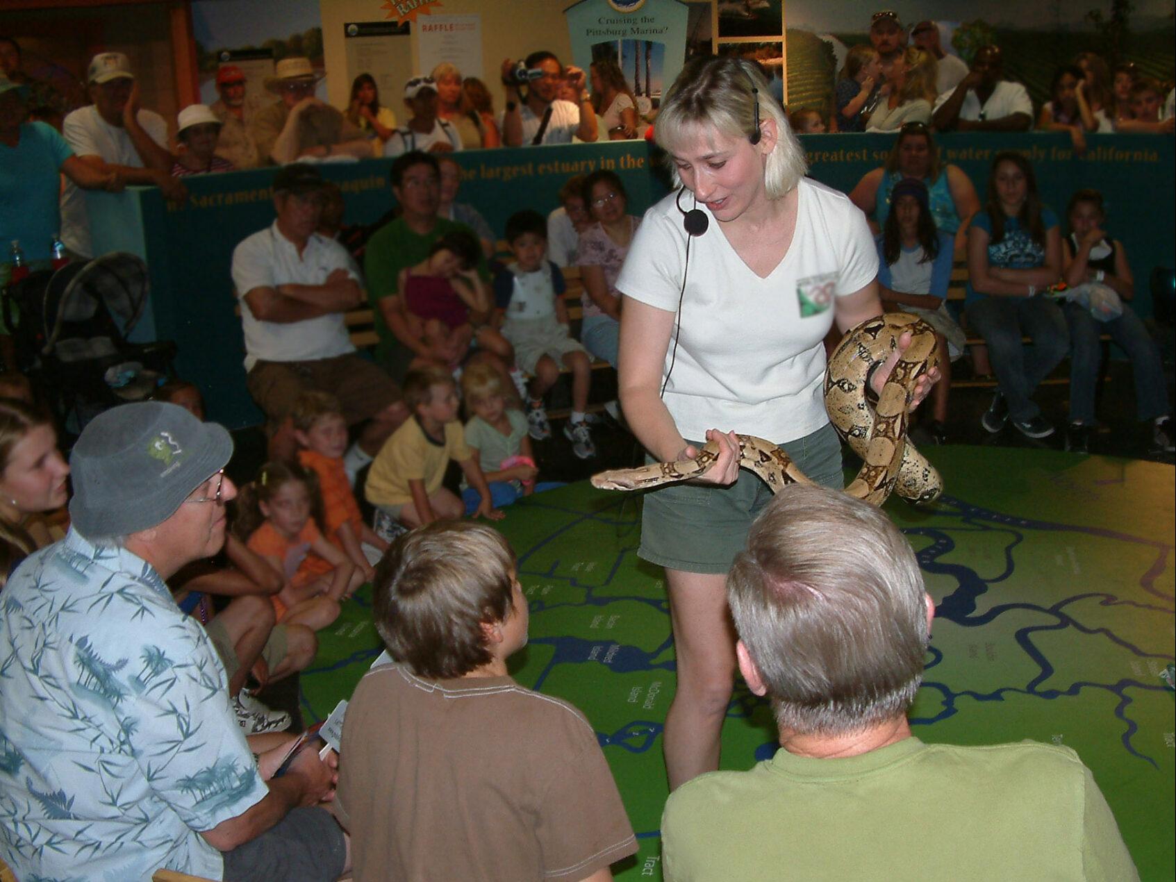 PIcture of Joy holding a snake with an audience around her