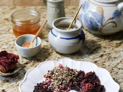 Picture of tea spices on a plate with a tea pot, honey, cream and sugar